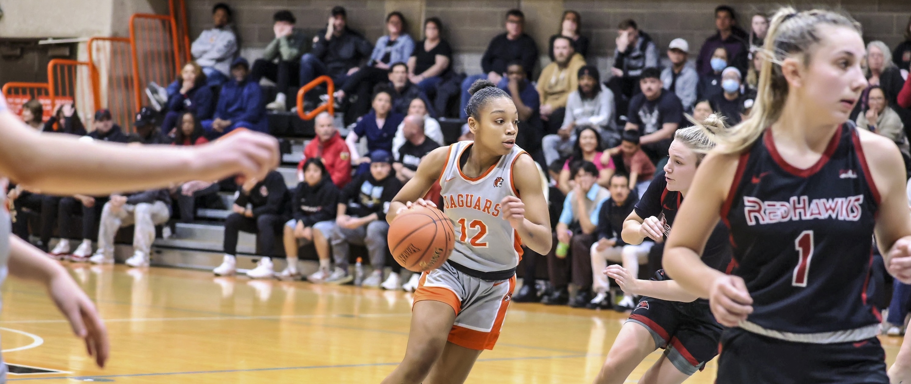 GovState basketball player dribbling the ball up the court against the opposing team